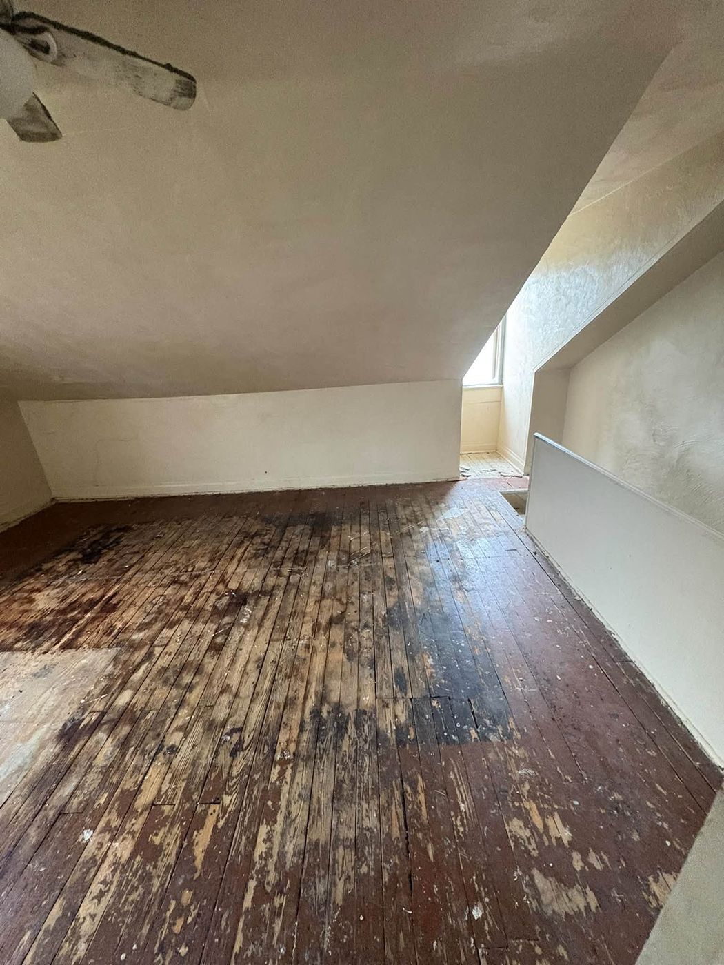 Attic room with damaged wood floor