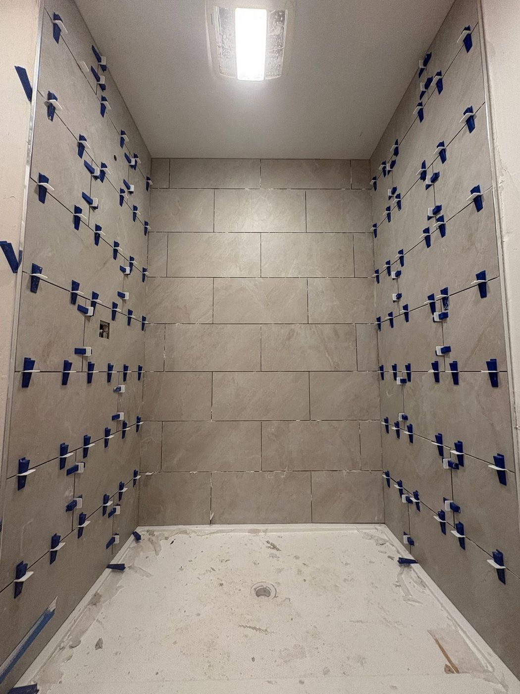 Shower tile being set with leveling clips
